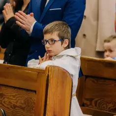 Chłopiec w okularach i albie czeka na komunię, pewnie w trzeciej klasie.