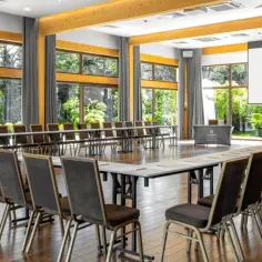 Sala konferencyjna w hotelu Kolumna Park z widokiem na zieleń. Ustawienie stołów w kształt podkowy, gotowa na spotkanie.