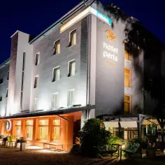 Hotel Perła Kraków nocą. Elegancki budynek z podświetlanym logo i oknami.