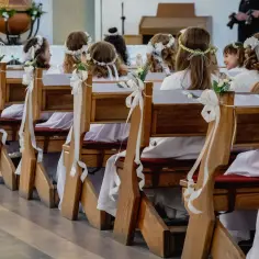 Dzieci w bieli, z wiankami na głowach, siedzą w ławkach kościelnych. Zastanawiasz się, ile trwa msza komunijna?