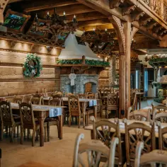 Drewniana, przytulna restauracja "Przystań w Kabanosie" z kamiennym kominkiem i tradycyjnymi zdobieniami.