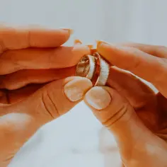 Dłonie trzymające dwie obrączki, symbolizujące miłość i wierność. Na której ręce nosi się obrączkę?