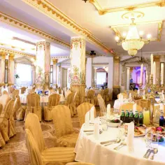 Elegancka sala bankietowa hotelu Książę Poniatowski, udekorowana złotem i kryształowymi żyrandolami, gotowa na przyjęcie gości.