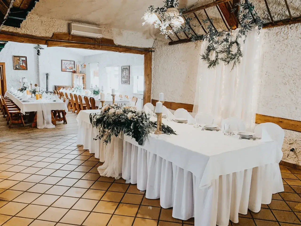 Elegancko nakryte stoły w karczmie u Michelle, ozdobione świecami i kwiatami, czekają na gości.