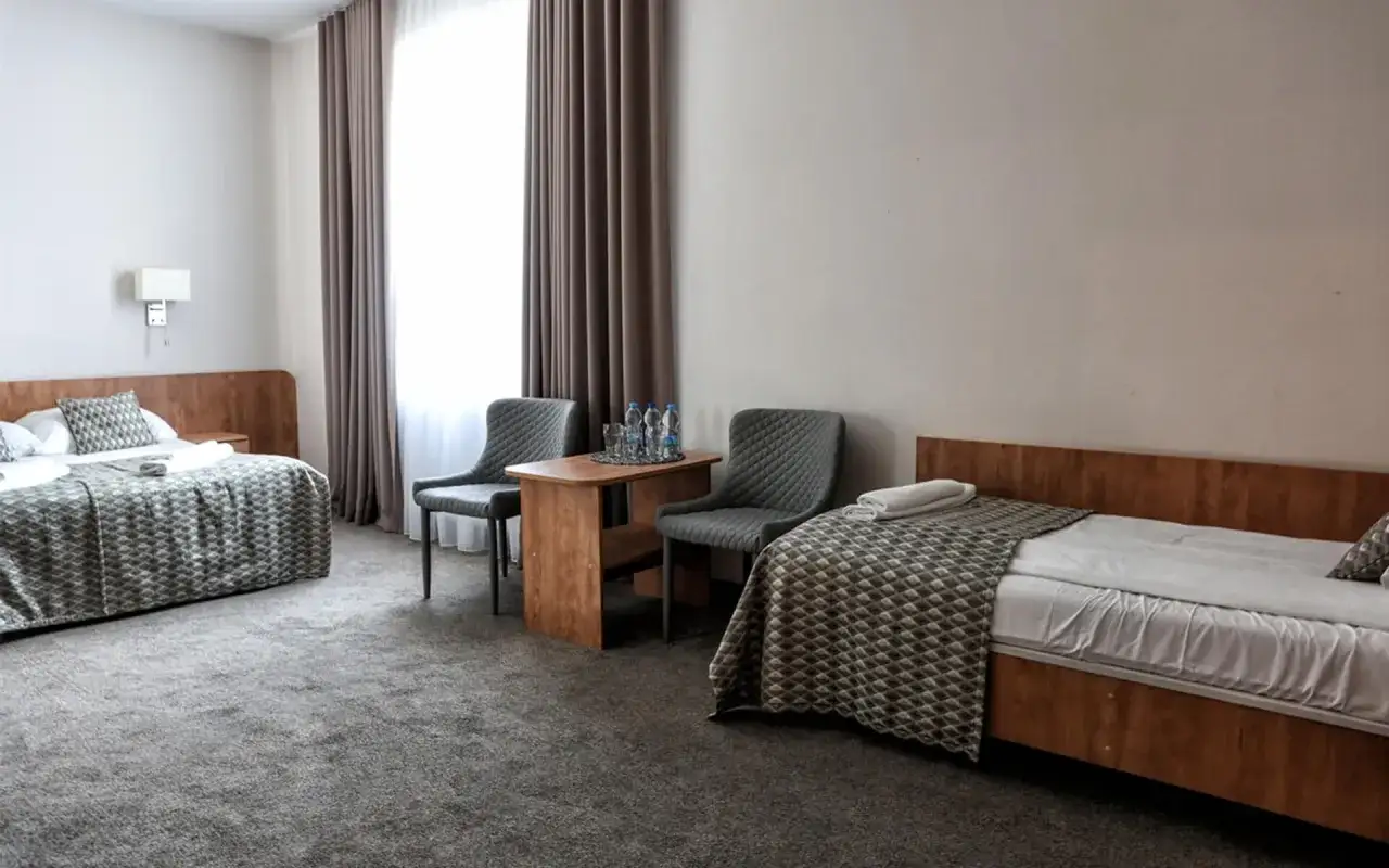 Pokój w hotelu Jan Sander z dwoma łóżkami, stolikiem i krzesłami.
