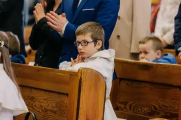 Chłopiec w okularach i albie czeka na komunię, pewnie w trzeciej klasie.