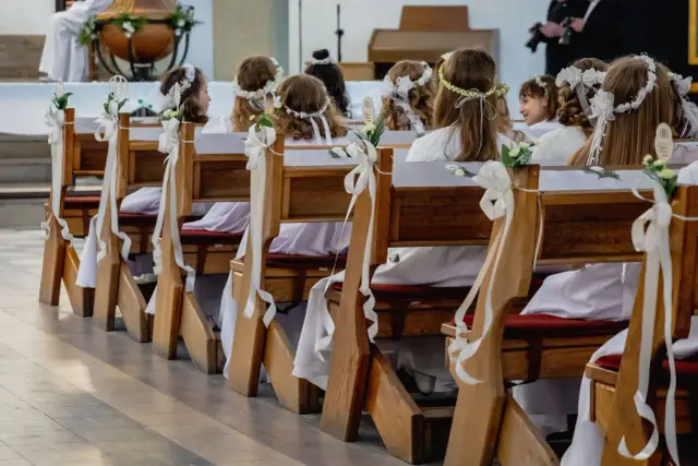 Dzieci w bieli, z wiankami na głowach, siedzą w ławkach kościelnych. Zastanawiasz się, ile trwa msza komunijna?